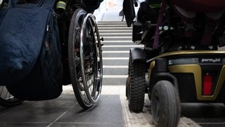 Symbolbild: Zwei Rollstuhlfahrer vor einer Treppe. Die Kreuznacher Diakonie hat in einer ihrer Einrichtungen für Menschen mit Behinderungen falsch abgerechnet. 