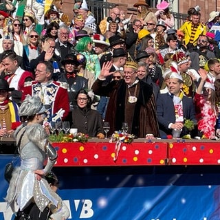 Vor dem Mainzer Staatstheater führt der Rosenmontagszug an der Tribüne mit prominenten Besuchern und Besucherinnen vorbei.