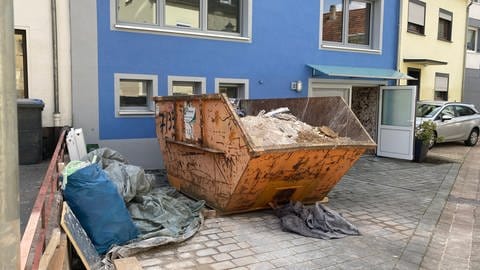 In Kordel stehen vier Wochen nach dem Hochwasser Mitte Juli immer noch Container mit Bauschutt in den Straßen