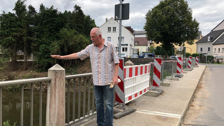 Dieser Einwohner von Holsthum zeigt wo das Wasser stand. Die Pfeiler der Brücke habe man nicht mehr gesehen. Doch die Arbeiten kämen flott voran, die weggespülten Bürgersteige wurden schon erneuert
