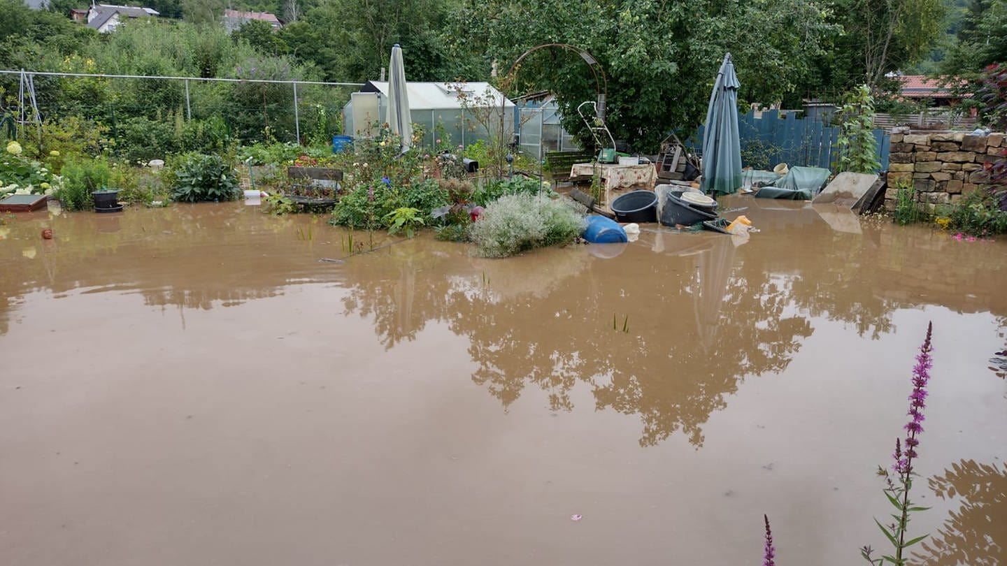 Der Garten steht komplett unter Wasser. Nur das Gewächshaus ragt heraus.