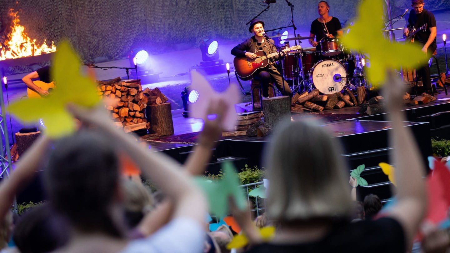 Johannes Oerding, Popsänger und Songwriter, steht mit seiner Band bei einem Konzert auf einer Open Air Bühne.