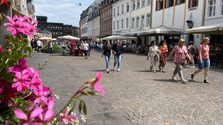 Passanten laufen entlang der Fußgängerzone in Trier, im Hintergrund die Porta-Nigra: Einzelhändler rechnen wegen des Feiertags in Luxemburg am 23.06. mit mehr Kunden