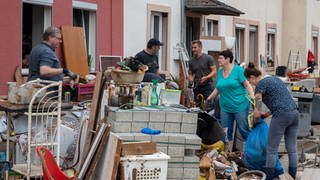 Menschen räumen im Stadtteil Ehrang die Schäden nach dem Hochwasser der Kyll auf. Zahlreiche Häuser im Ort waren betroffen, Bewohner mussten evakuiert werden.