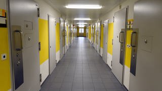 Ein Gang mit Haftzellen in der Justizvollzugsanstalt (JVA) Wittlich. Ein Gefängnismitarbeiter soll Häftlinge bei Einkäufen über den Tisch gezogen haben. Der Mann muss sich wegen Betrugs am Landgericht Trier verantworten.