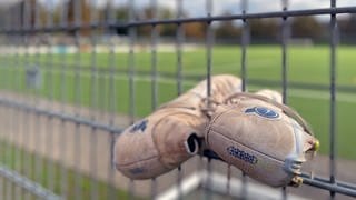 Fußballschuhe hängen am Zaun im Moselstadion in Trier