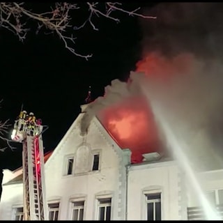 Feuerwehrleute beim Löschen des Brandes in einem Wohn- und Geschäftsgebäude in Neuerburg in der Eifel. 