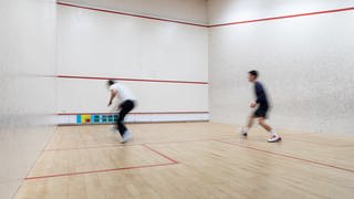 Zwei Squash-Spieler in einer Squash-Halle. 