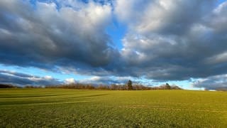Wolken und Sonne bei einem Feld bei Reinsfeld