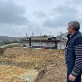 Alfred Wirtz blickt auf die Baustelle in Olk. Trotz baugenehmigung konnten die Bauherren nun erst mit den Projekten starten. 