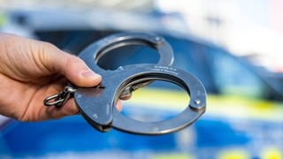 Handschellen vor einem Polizeiauto - nach dem Überfall auf eine Tankstelle in Konz wurde ein Verdächtiger festgenommen