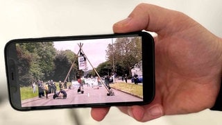 Klimaaktivisten blockieren die Bundesstraße entlang des Moselufers in Trier mit einem Holzgestell.