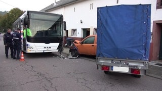 Der Schulbus stießt mit einem geparkten Auto und einem geparkten Traktor zusammen