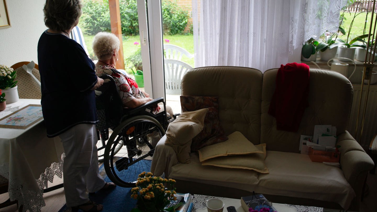 Pflegekraft mit Seniorin im Rollstuhl