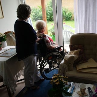 Pflegekraft mit Seniorin im Rollstuhl