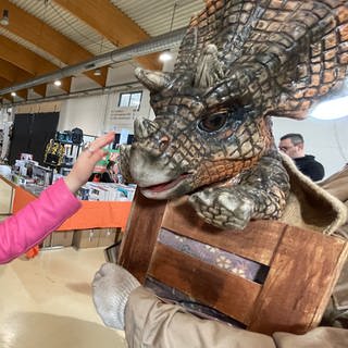 Proud Nerd Convention in Trier. Die kleine "Mandalorianerin" bestaunt einen Baby-Dino aus Jurassic Park. 