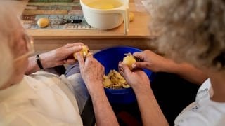 Eine Angehörige versucht den Alltag mit einem Demenzkranken zu meistern. Hier schälen sie gemeinsam Kartoffeln.