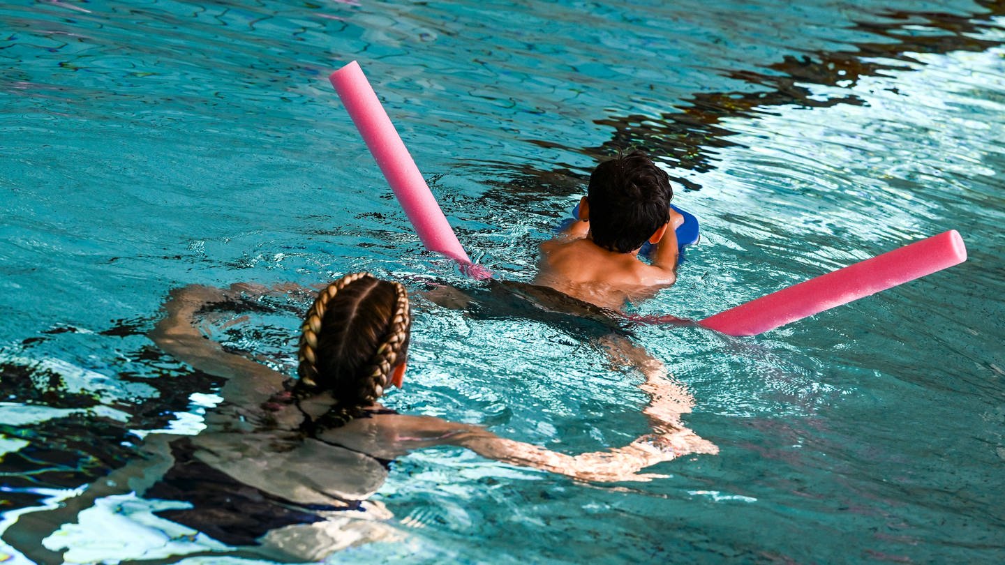 Ein Kind erhält Schwimmunterricht in einem Schwimmbad / In der Region Trier müssen Kinder teils ein Jahr lang auf einen Schwimmkurs warten.