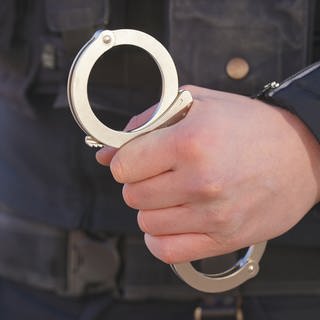 Ein Polizist mit Handschellen. Ein Mann muss in Trier nach versuchtem Totschlag für mehr als sieben Jahre in Haft. Die Richter sahen es als erwiesen an, dass er auf einen Freier eingestochen hatte. 