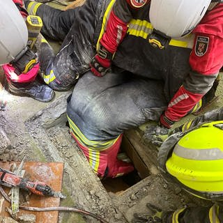 Ein Trierer Feuerwehrmann zwängt sich durch einen Schacht, um Überlebende aus einem eingestürzten Hotel in Kröv zu retten