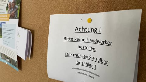 Hinweis an der Pinnwand im Treppenhaus: Die Stadtbürgermeisterin warnt die Bewohner davor, selbstständig Handwerker zu bestellen. Denn sie würden auf den Kosten sitzen bleiben. 