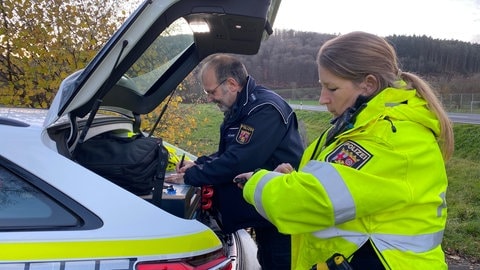 Helmut Römer schreibt den Mängelbericht zu einem Auto, Hilke Mußweiler nennt ihm dafür die genaue Uhrzeit der Kontro