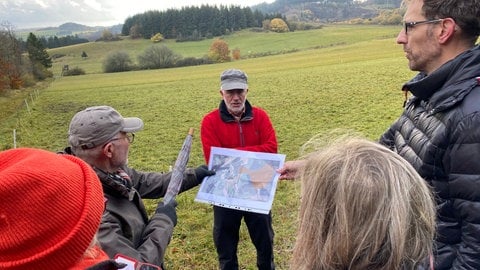 Sepp Wagner (Mitte) vom NABU Daun zeigt, wo der Scharteberg bei der Sprengung schon angetastet wurde.