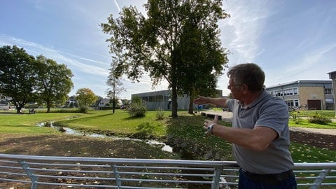 Vor der Renaturierung hat der Bach eine klare Kurve an den Bäumen und Sträuchern vorbei genommen, zeigt Bauingenieur Jürgen Mathar. Jetzt darf der Bach wieder ruhig durch sein ursprüngliches Bett mäandern.