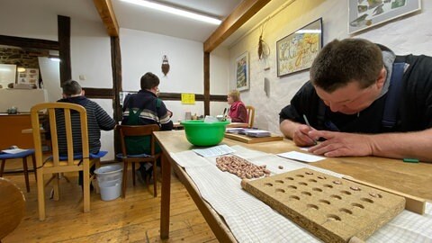 In der Gartenwerkstatt der Weggemeinschaft Vulkaneifel werden Bohnen sortiert und abgepackt.