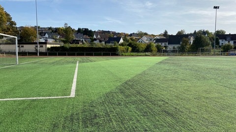 Dort, wo noch das Granulat auf dem Hillesheimer Sportplatz fehlt, kann man sehen, wo unterirdisch jetzt ein Teil des Bachs verläuft. Der Rest fließt in seinem alten Bett um den Platz herum, wodurch 120 Meter zusätzlich für das Wasser gewonnen wurden.