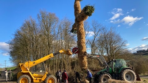 Die Vorbereitungn zum Hüttenbrennen in Brecht in der Eifel laufen auf Hochtouren. Das Kreuz wird mit einem Bagger aufgestellt. 