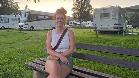 Katharina Rodermund auf einer Bank auf dem Platz des Reisemobilparks Klüsserath an der Mosel. Weil die Straße zwischen dem Ort und Trittenheim wegen Sanierungsarbeiten seit einem Jahr komplett gesperrt ist kommen kaum Urlauber. Die Baustelle wird immer mehr zum Problem für sie.