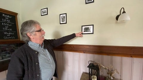 Günter Schmitz zeigt auf ein altes Bild, auf dem zu sehen ist, wie der Gasthof bei seiner Gründung 1912 aussah. Günter Schmitz' Großvater hatte ihn damals als "Gasthof Zum Bahnhof" eröffnet.