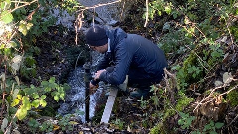 Matthias Heck vom NABU Südeifel entnimmt eine Probe an der Stelle, an der die Kläranlage Dudeldorf Wasser in den Langebach leitet.