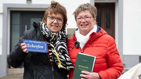 Helga Scherf (links) hatte die Idee, in Bonerath wieder alte Hausnamen anzubringen. Die Vorsitzende des Heimat- und Kulturvereins Gabi Theis (rechts) hat diese Idee in Zusammenarbeit mit den Mitgliedern und Dorfbewohnern umgesetzt.