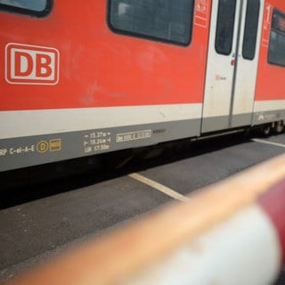 Ein Zug fährt über einen Bahnübergang, an dem die Schranke geschlossen ist.