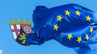 Eine wehende Europaflagge und ein Rheinland-Pfalz Wappen