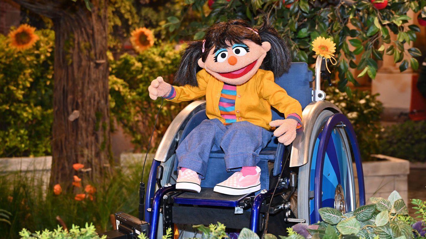 Elin zieht in die Sesamstraße, das Mädchen ist sieben Jahre alt und nutzt einen Rollstuhl.