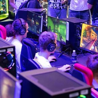 Symbolfoto Messe Gamescom: Besucher spielen an Spielkonsolen