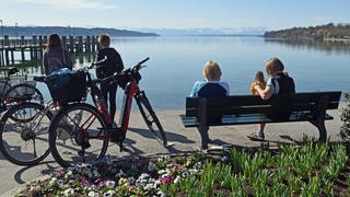 E-Bikes Ausflügler genießen an der Seepromenade die Sonne