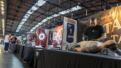 Ein Tätowierer tätowiert einen Kunden bei der Tattoo Convention in Berlin.