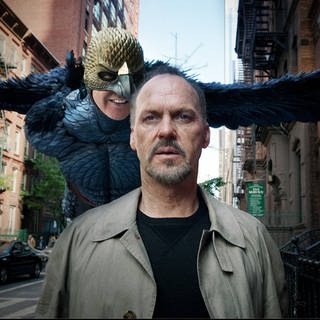 Szenenbild aus "Birdman" mit Michael Keaton im Vordergrund. Direkt hinter ihm fliegt Birdman und flüstert ihm ins Ohr