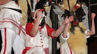 Mit Masken aus Federn und Fell verkleidete Männer des Vereins Borkumer Jungens stürzen sich in der Innenstadt der Nordseeinsel in die Arme von Schaulustigen. 