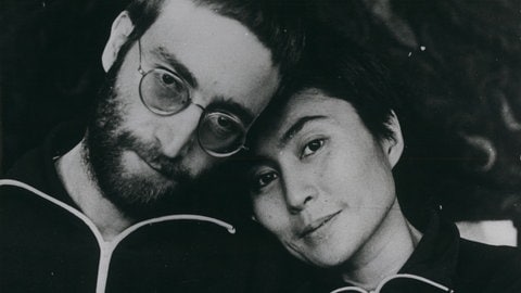 John Lennon (links) und Yoko Ono blicken für ein Schwarzweiß-Porträt in die Kamera, 1970.