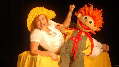 Eine Handpuppe mit roten Haaren und eine Schauspielerin, die zum Ensemble des Mainzer Kindertheaters gehört
