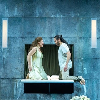 Verdis "Otello" am Theater Ulm: Desdemona (Maryna Zubko) und Otello (Rodrigo Porras Garulo) kniend auf ihrem Brautbett. Sie schauen einander an.