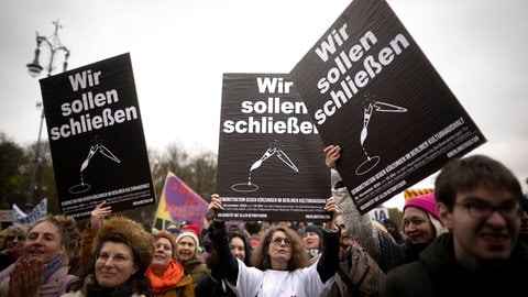 Protestierende tragen schwarze Plakate mit der Aufschrift "Wir sollen schließen" und einem zerbrochenen Malerpinsel