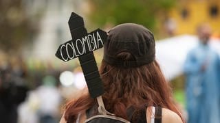 Demonstrantion mit einem Pappkreuz mit der Aufschrift Columbia