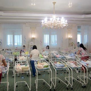 Hotelzimmer mit Leihmüttern und Leihmutterbabys, die auf Abholung ihrer ausländischen Eltern warten. 