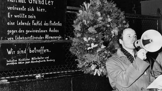 Pastor Ulfried Kleinert hält vor der Gedenktafel eine Rede. Am 22.11.1977 wurde vor der Petri-Kirche in Hamburg an der Stelle, an der sich der Tübinger Lehrer Hartmut Gründler aus Protest gegen die Kernenergie verbrannt hatte, eine Gedenktafel enthüllt.